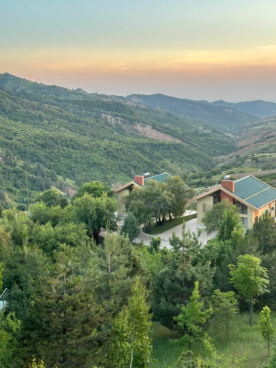 A picturesque evening view of Amirsoy, with lush green hills and charming cottages nestled in the valley.