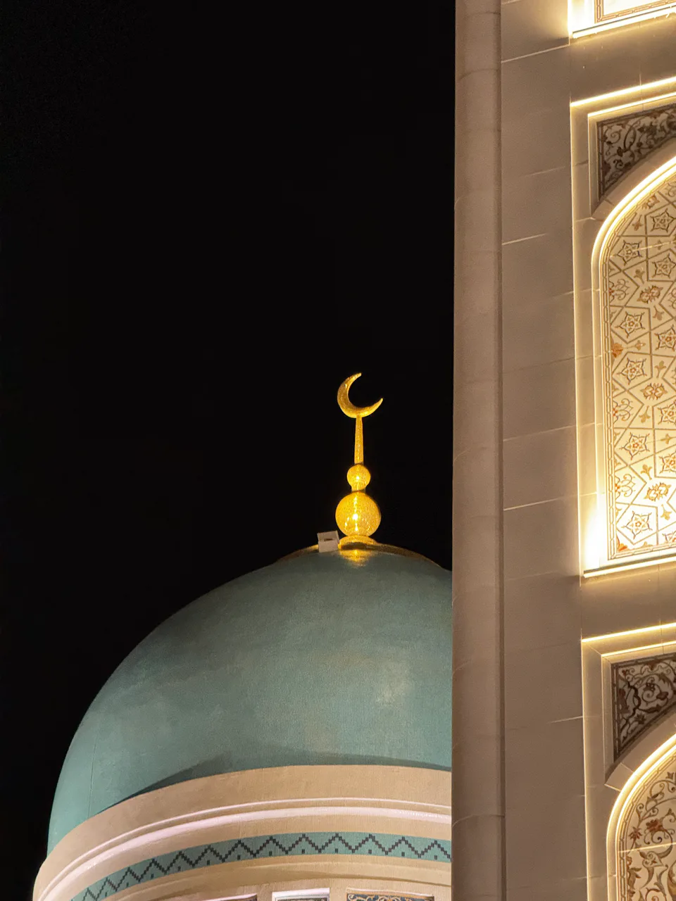 Dome of a mosque near the Imam al-Bukhari Mausoleum complex in Samarkand, Uzbekistan, photographed at night. The turquoise dome is topped with a golden crescent finial, characteristic of Islamic archi